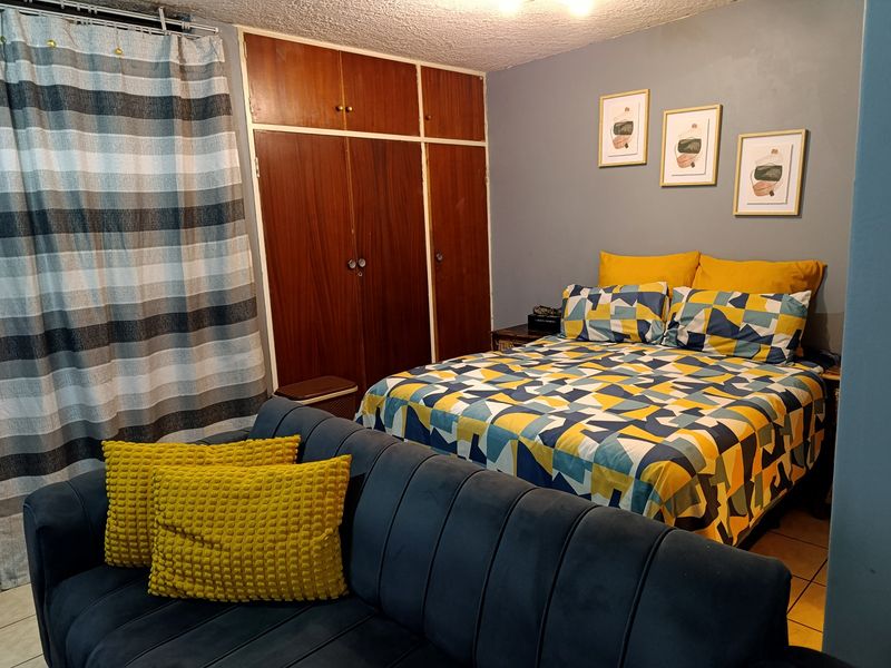 A bedroom featuring built-in wooden wardrobes, tiled flooring, and a textured ceiling, offering a functional space with potential for modern updates.