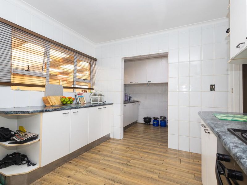 Functional kitchen featuring laminate countertops, tiled splashbacks, built-in cabinetry, and an integrated hob and oven, with an adjacent scullery area.
