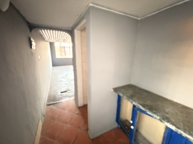 A small, empty kitchen area featuring tiled flooring and a basic built-in counter, requiring cosmetic updates to improve functionality and aesthetic appeal.
