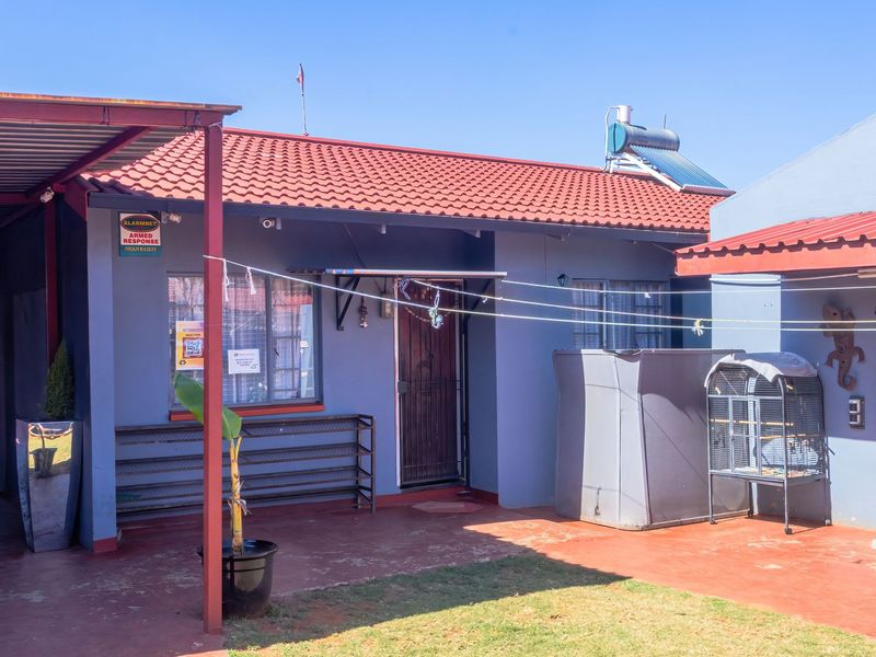 Rear exterior view of the house featuring a covered patio area, metal roofing, and a solar water heating system.