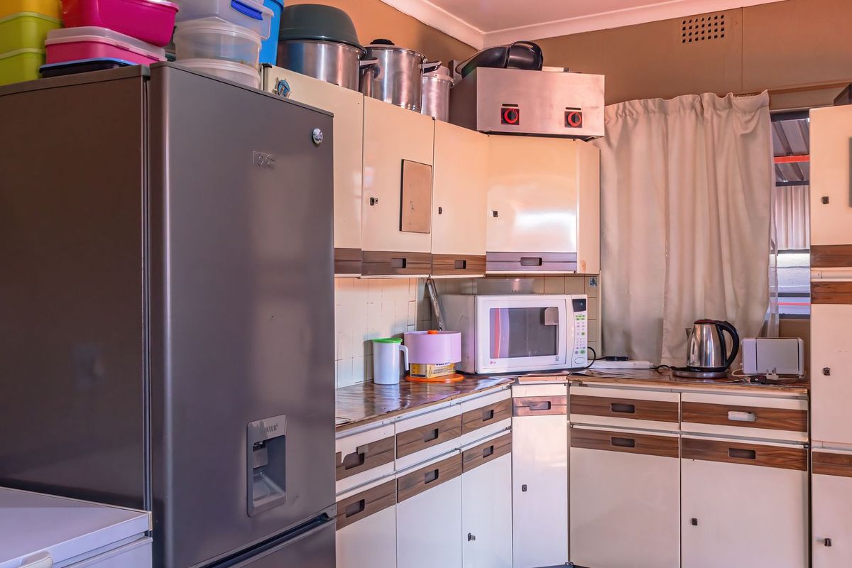 A dated kitchen featuring original built-in cabinetry, laminate countertops, and a tiled backsplash, offering potential for a modern renovation.