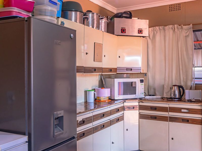 A dated kitchen featuring original built-in cabinetry, laminate countertops, and a tiled backsplash, offering potential for a modern renovation.