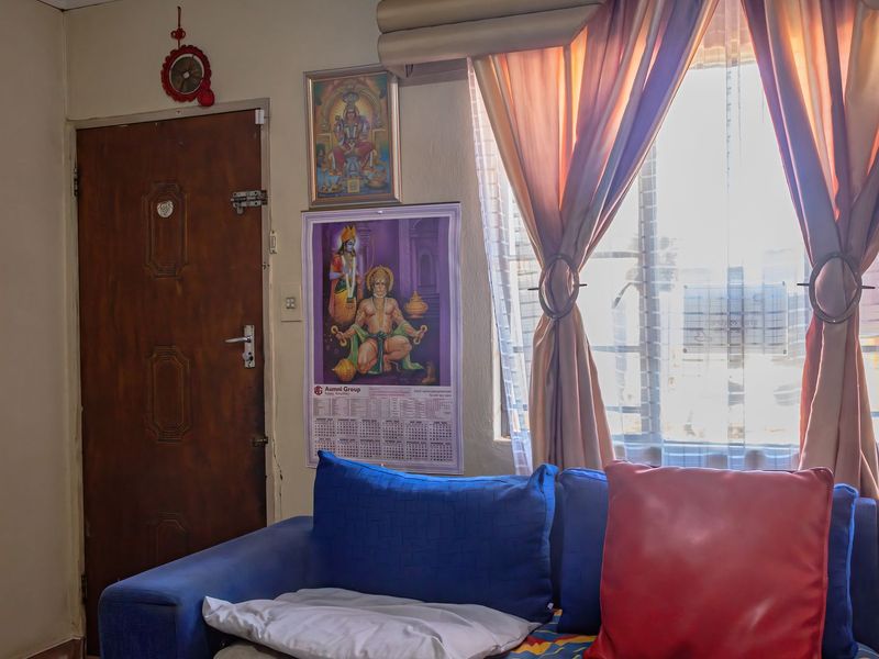 A living room area featuring a window with curtains and a wooden door, providing a functional and lived-in space.