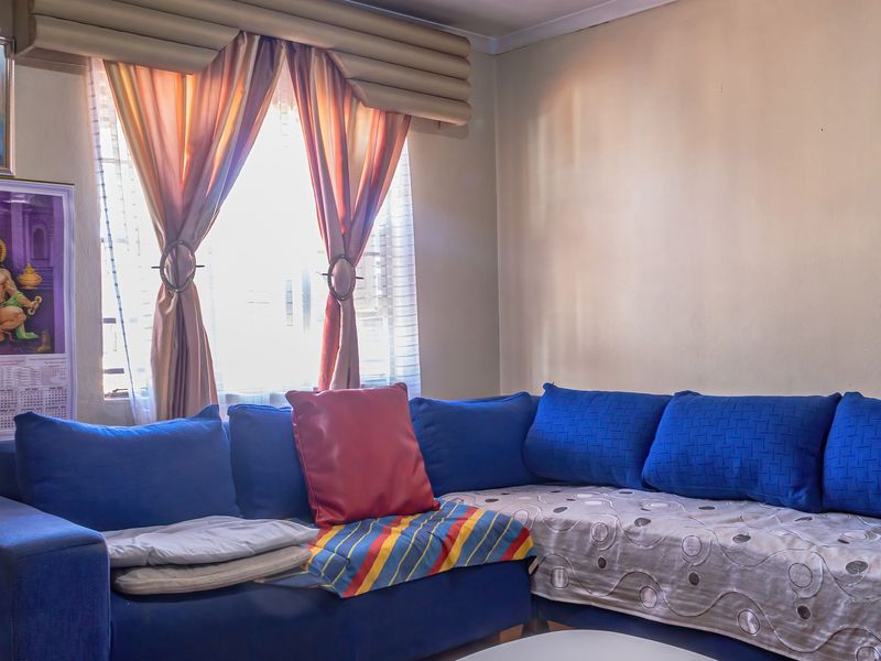 A living room area featuring a window with installed curtain rods and neutral wall finishes.