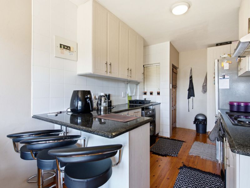 A functional kitchen featuring granite countertops, ample built-in cabinetry, a tiled backsplash, and warm timber flooring, providing a practical workspace.