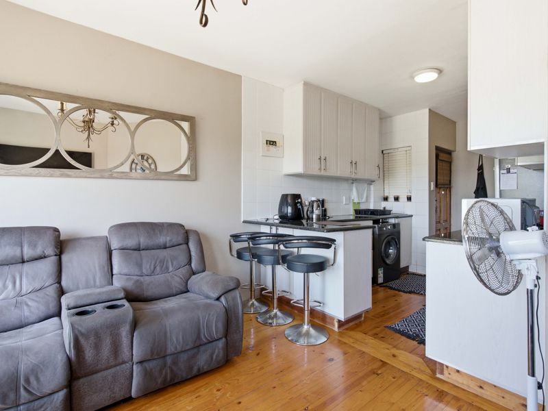 Open-plan living and kitchen area featuring hardwood flooring, built-in cabinetry with granite countertops, and a tiled kitchen backsplash.