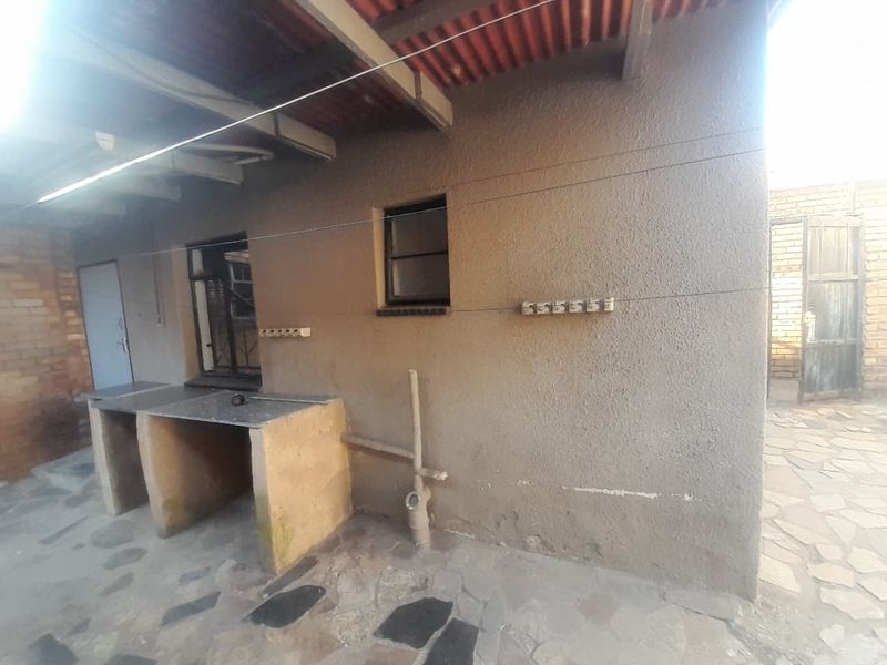 Covered outdoor patio area featuring stone paving, a built-in concrete prep counter, and exposed exterior wall finishes.