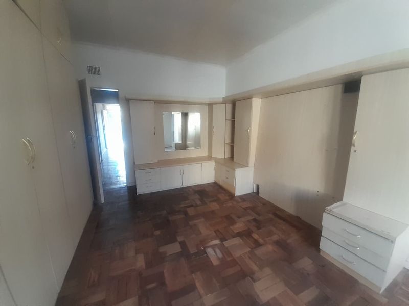 Bedroom featuring extensive built-in cabinetry, a vanity unit, and traditional parquet flooring, offering ample storage space in a dated interior.