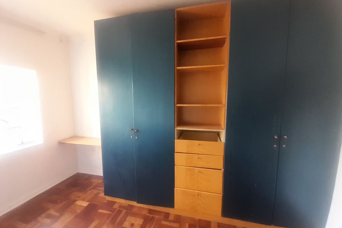 Bedroom featuring parquet flooring and built-in cupboards with an integrated desk area, requiring minor repairs to cabinetry.