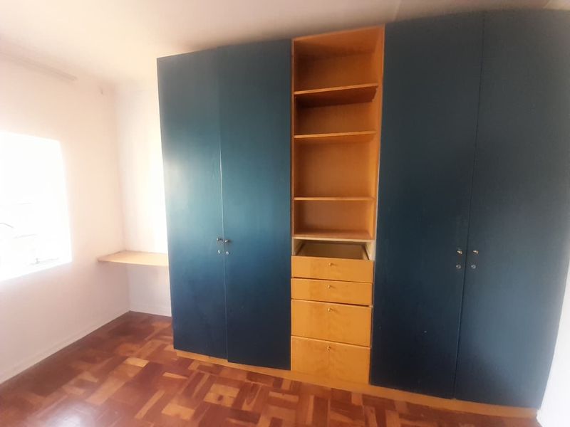 Bedroom featuring parquet flooring and built-in cupboards with an integrated desk area, requiring minor repairs to cabinetry.