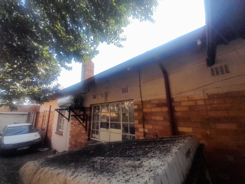 Rear exterior view of the house featuring brick facade, steel frame windows, and a mounted solar geyser system.
