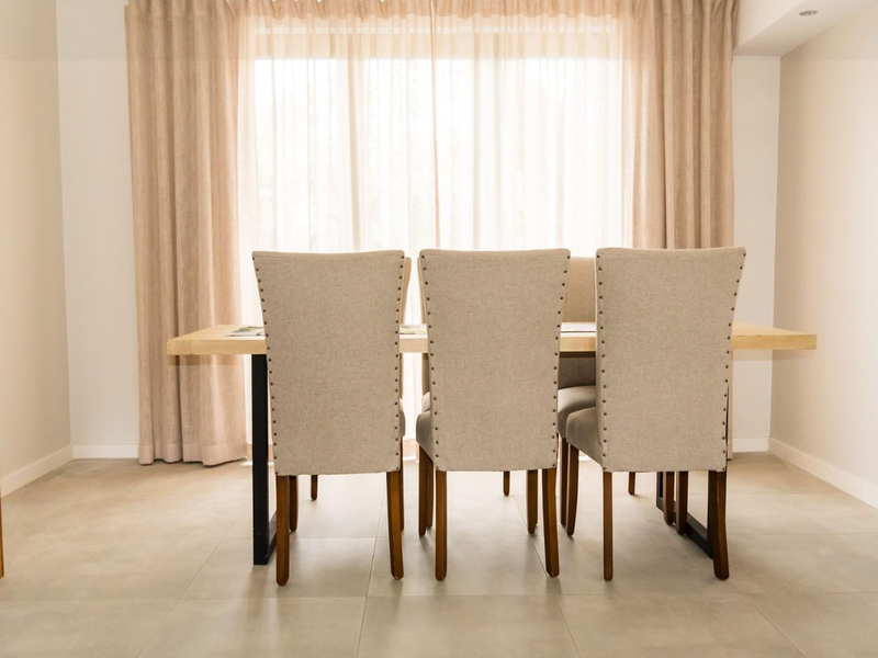 A bright and modern dining area featuring neutral tiled flooring and recessed ceiling lighting, creating a clean and inviting space for meals.