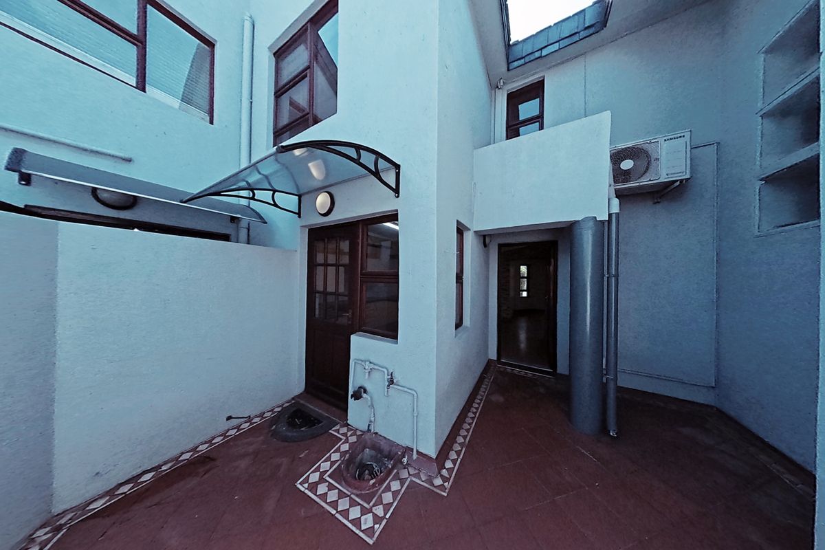 A rear courtyard area featuring tiled flooring, an external water tap, and an air conditioning unit, providing a functional outdoor space for the townhouse.