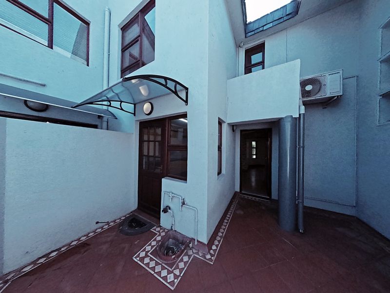 A rear courtyard area featuring tiled flooring, an external water tap, and an air conditioning unit, providing a functional outdoor space for the townhouse.