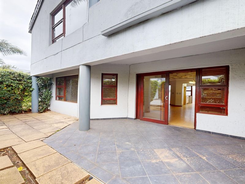A covered patio area featuring tiled flooring and sliding glass doors providing access to the interior living space.