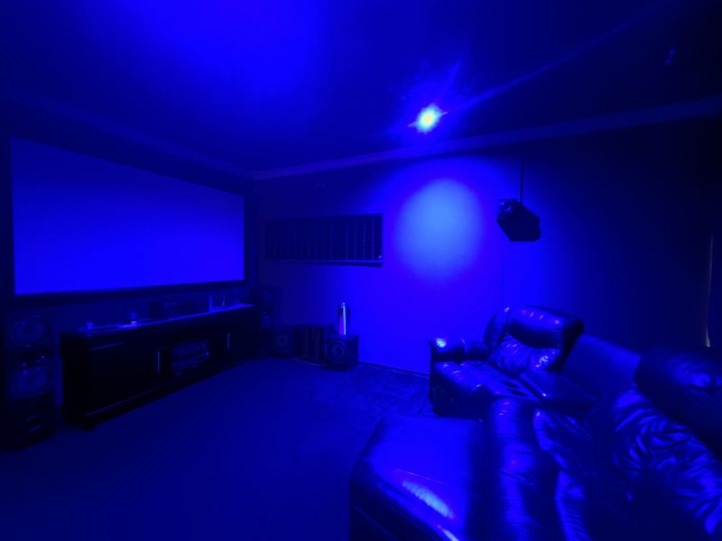 Dedicated home cinema room featuring a large projector screen, acoustic wall treatments, and ceiling-mounted projection equipment for an immersive viewing experience.