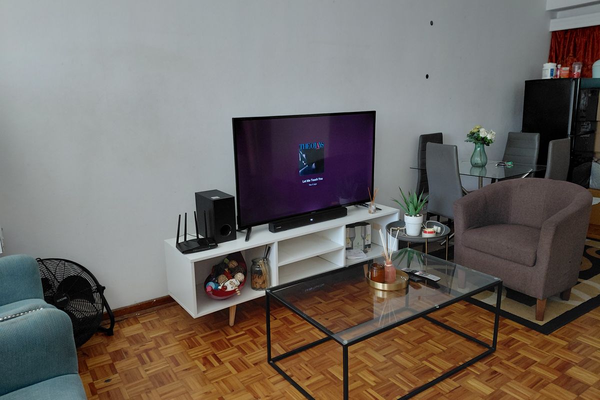 A living room area featuring classic parquet flooring and neutral wall finishes, providing a functional space for relaxation and dining.