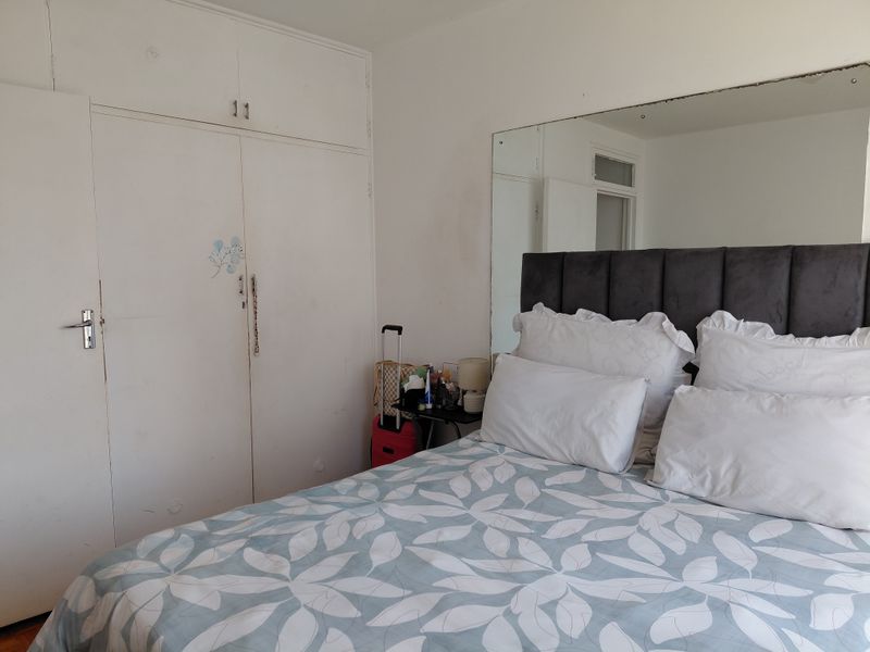 A bedroom featuring built-in cupboards and a large wall-mounted mirror, providing functional storage and reflective space.