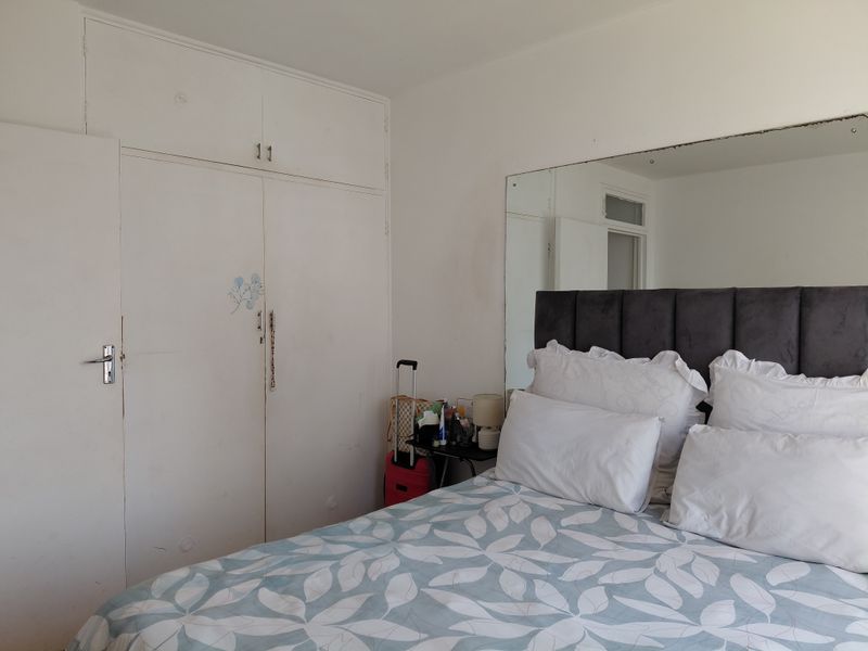 A bedroom featuring built-in cupboards with overhead storage and a large wall-mounted mirror above the bed area.