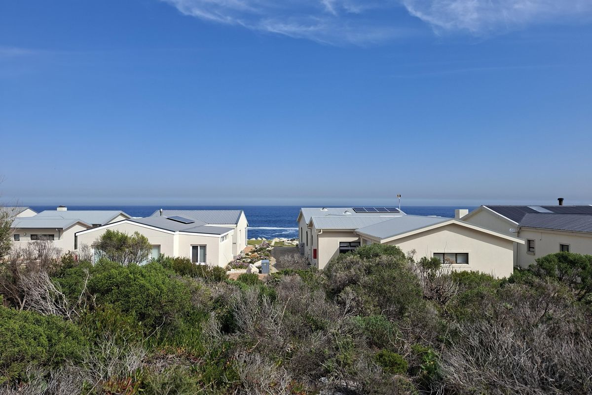 A scenic view overlooking coastal residential properties with a clear ocean horizon in the background.