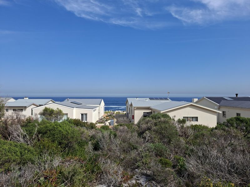 A scenic view overlooking coastal residential properties with a clear ocean horizon in the background.