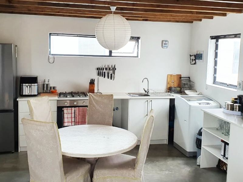 A functional kitchen featuring exposed timber ceiling beams, concrete flooring, gas hob, built-in oven, and ample fitted cabinetry.