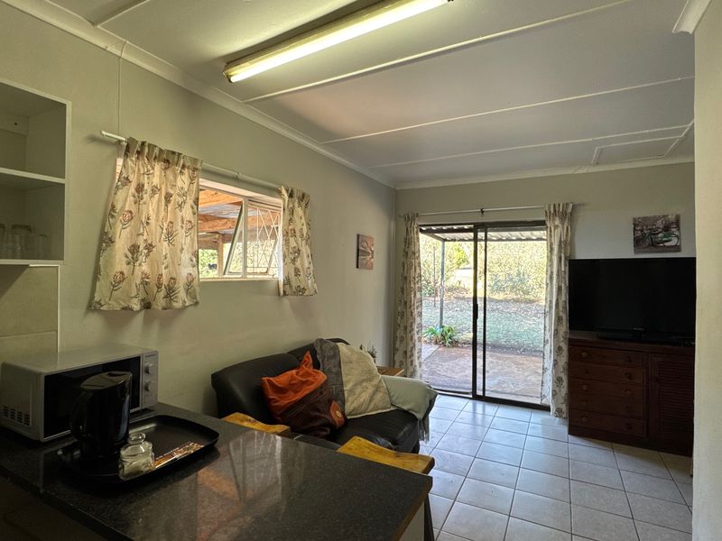 Open-plan living area featuring tiled flooring, built-in shelving, and a sliding glass door providing direct access to the outdoor patio area.