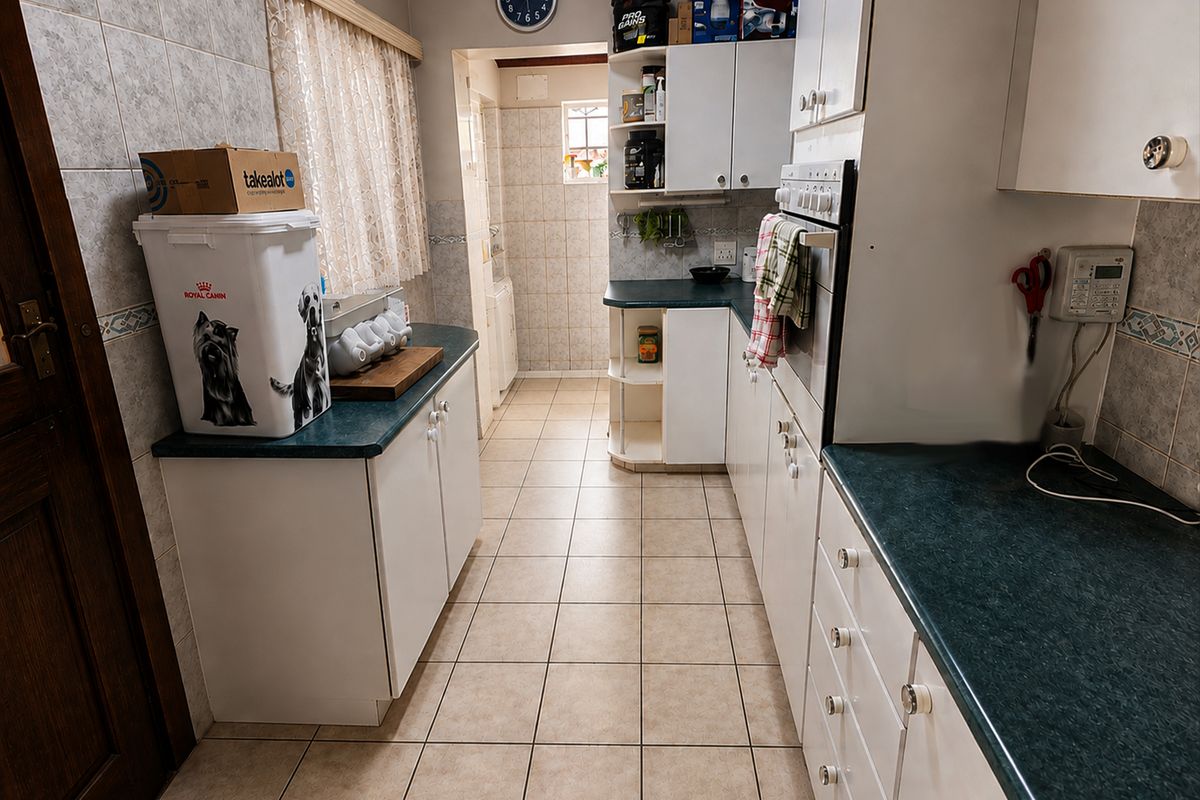 A functional kitchen featuring tiled flooring, ample built-in cabinetry, laminate countertops, and a built-in oven, offering a practical layout for daily meal preparation.