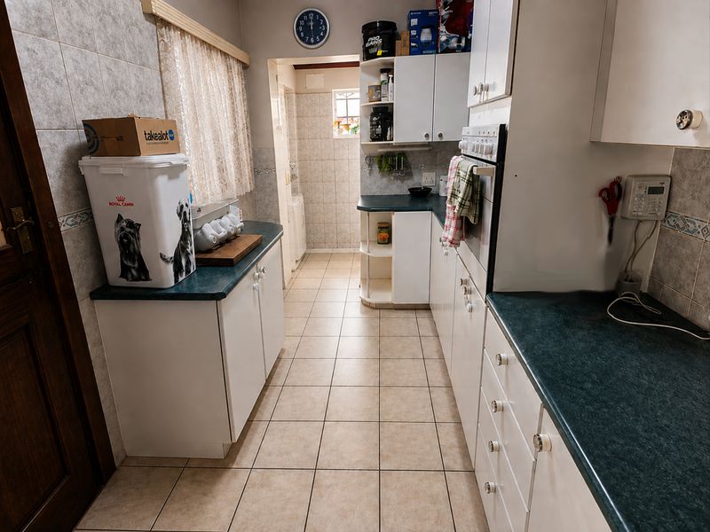 A functional kitchen featuring tiled flooring, ample built-in cabinetry, laminate countertops, and a built-in oven, offering a practical layout for daily meal preparation.