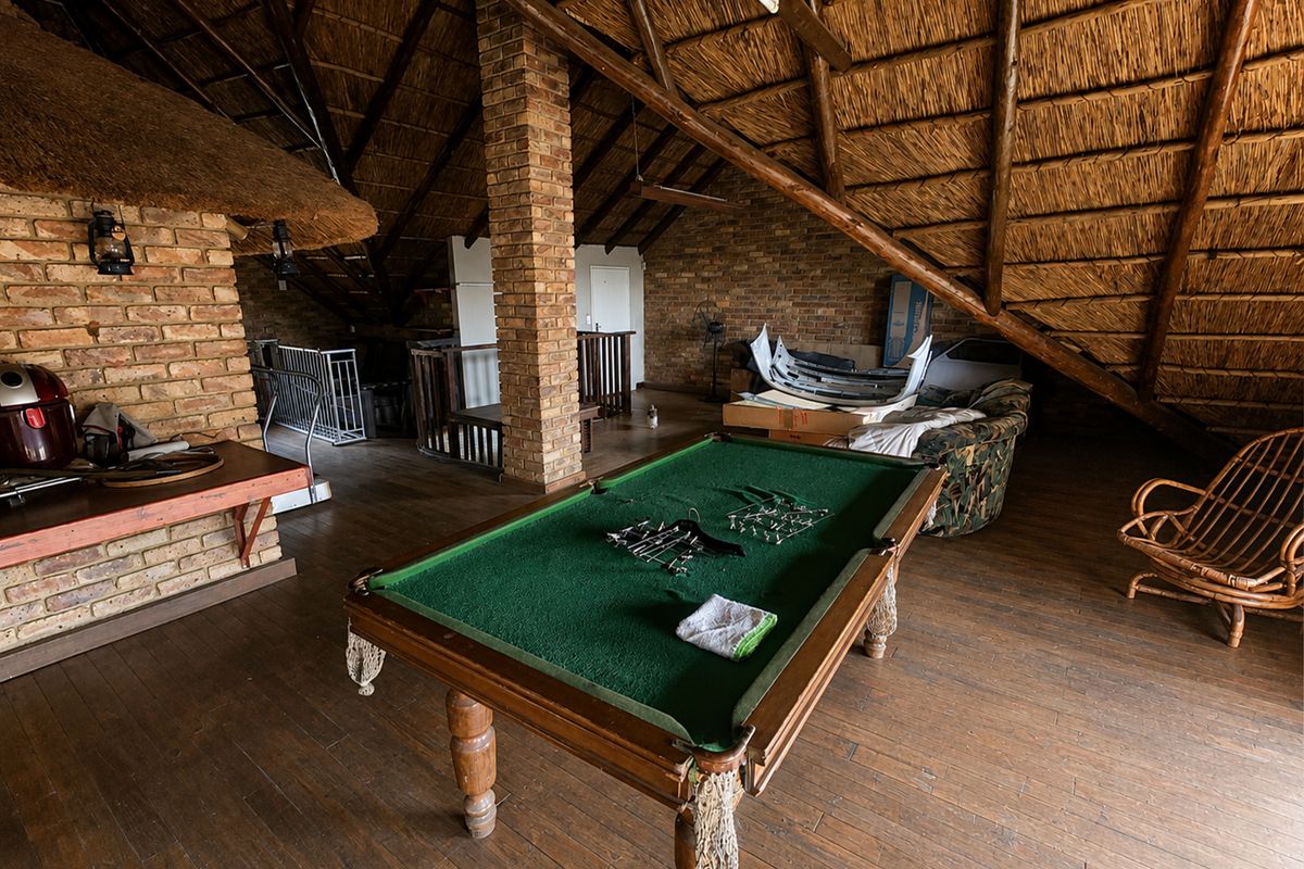 Spacious loft-style living area featuring exposed thatch roofing, timber rafters, and brick architectural elements, offering a rustic and versatile open-plan space.
