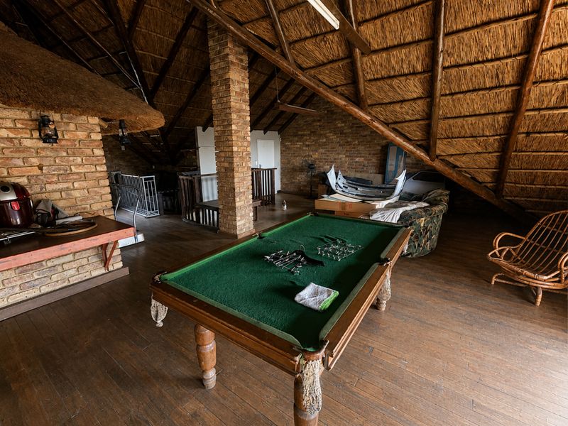 Spacious loft-style living area featuring exposed thatch roofing, timber rafters, and brick architectural elements, offering a rustic and versatile open-plan space.
