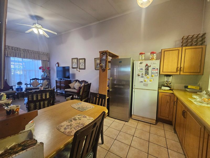 Open-plan living and kitchen area featuring tiled flooring, wooden cabinetry, and a ceiling fan, offering a functional layout for daily living.