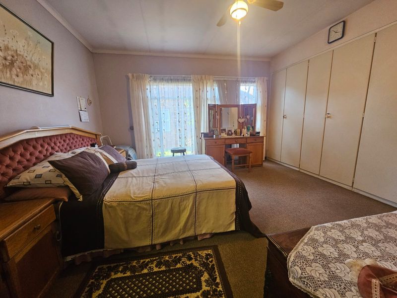 Spacious bedroom featuring built-in cupboards, a ceiling fan, and a sliding glass door providing access to the exterior.