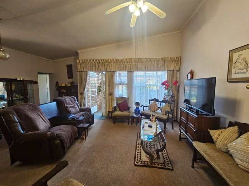Spacious living room featuring carpeted flooring, a ceiling fan, and direct access to an outdoor patio area through sliding glass doors.
