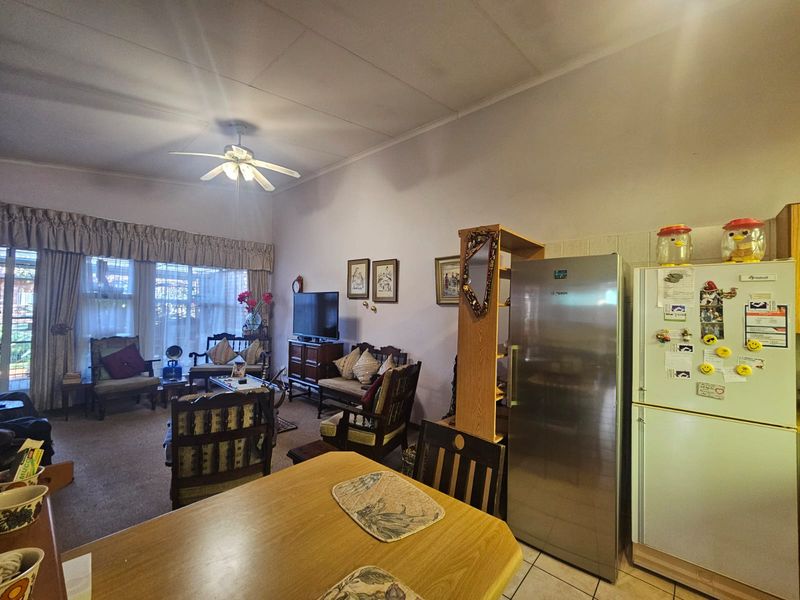 Open plan living and dining area featuring a ceiling fan, tiled and carpeted flooring, and sliding glass doors leading to the exterior.