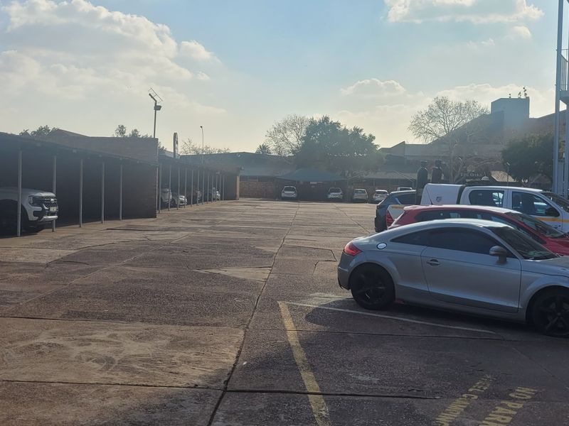 Outdoor parking area featuring covered parking bays and concrete paving, adjacent to the residential building structure.
