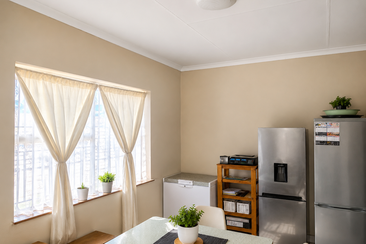 A functional kitchen area featuring a large window with natural light, neutral wall tones, and space for essential appliances.