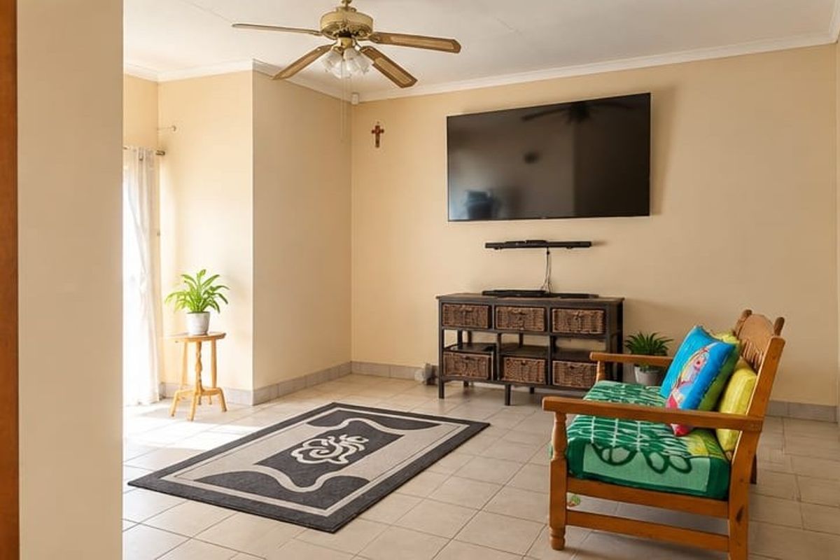 A bright living room featuring neutral walls, tiled flooring, and a ceiling fan, offering a comfortable and functional space.