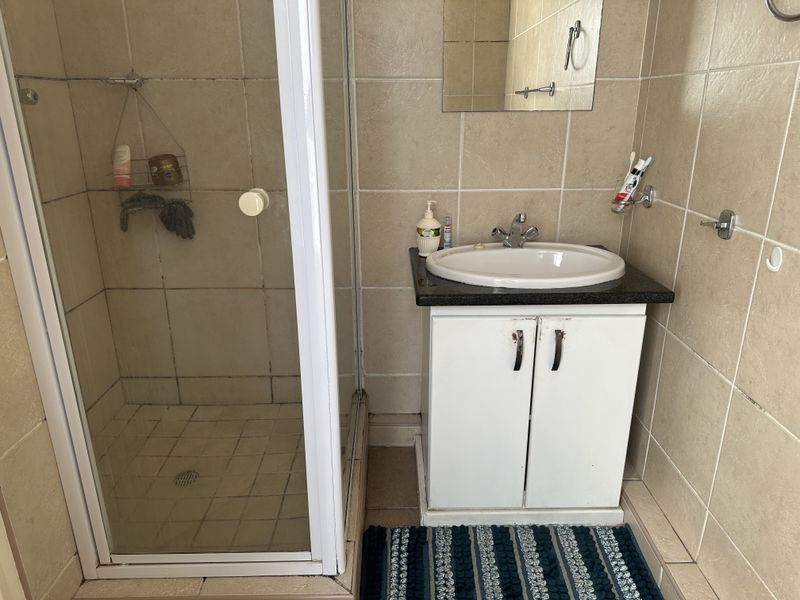 A functional bathroom featuring a shower enclosure, a vanity cabinet with a granite countertop, and tiled wall finishes.
