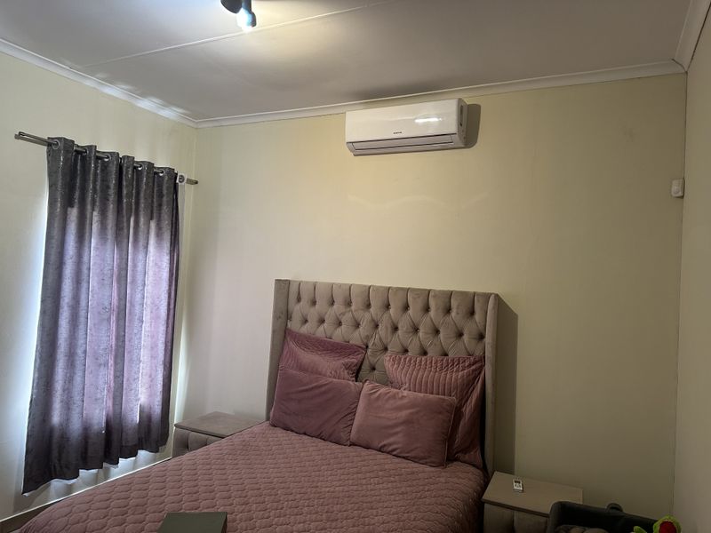 A bedroom featuring a wall-mounted split-system air conditioning unit and neutral wall finishes.