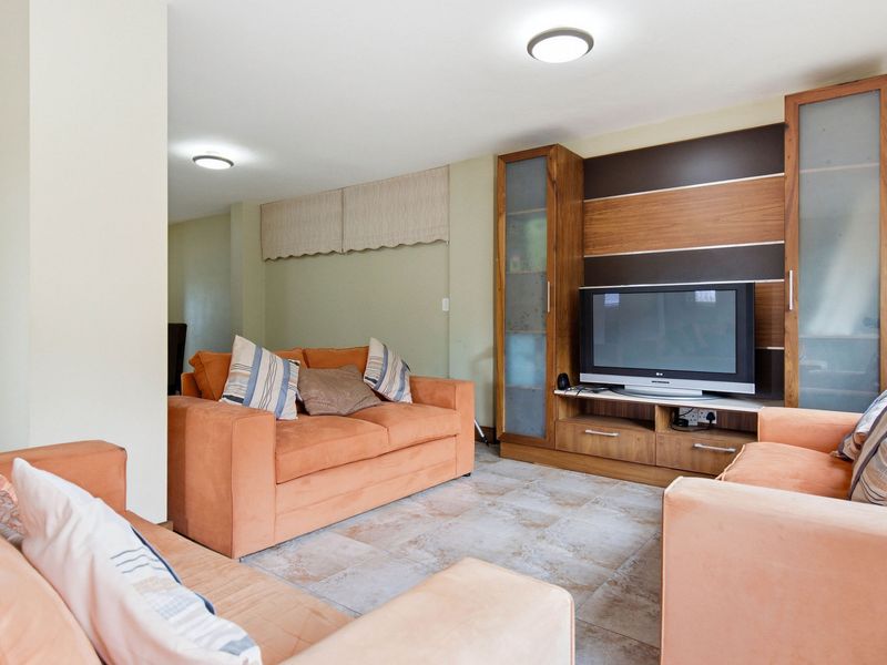 A comfortable living room featuring tiled flooring, built-in wooden cabinetry, and recessed ceiling lighting.