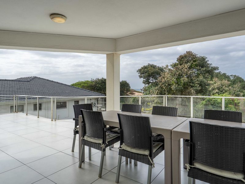 Spacious covered balcony featuring tiled flooring and a glass balustrade, offering an elevated outdoor area with scenic views.