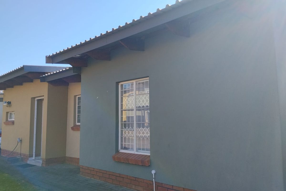 Rear exterior view of the townhouse featuring a tiled roof, exposed timber rafters, and security-fitted windows with a paved walkway.