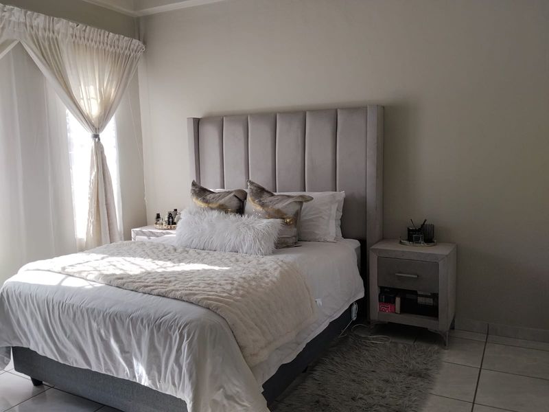 A well-maintained bedroom featuring neutral wall tones and tiled flooring, providing a comfortable and functional sleeping space.
