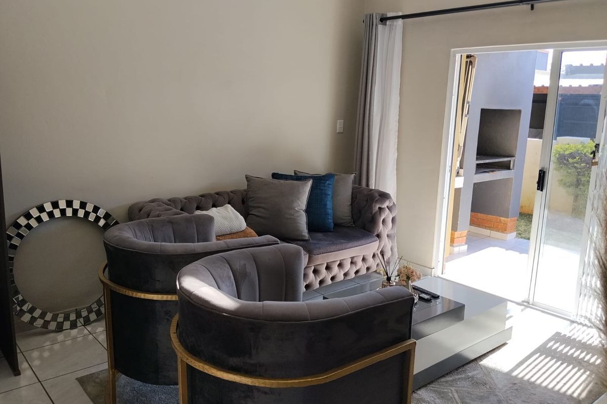 A bright living room featuring tiled flooring and a sliding glass door that provides direct access to an outdoor patio area.