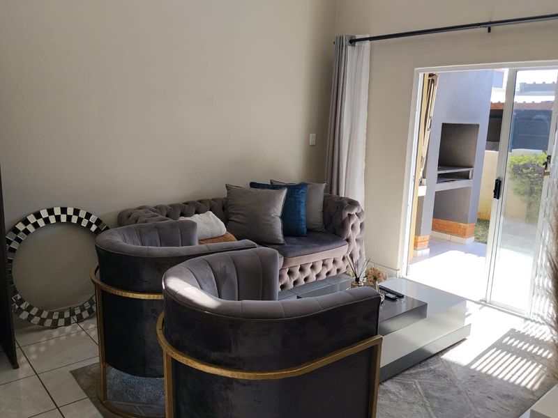A bright living room featuring tiled flooring and a sliding glass door that provides direct access to an outdoor patio area.