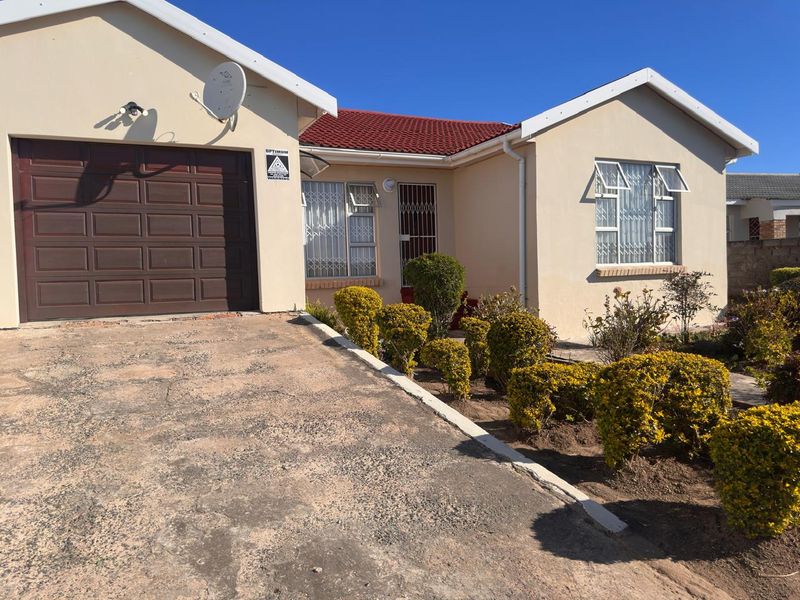 Front elevation of a single-story house featuring a single garage, tiled roof, and a concrete driveway with established garden shrubs.