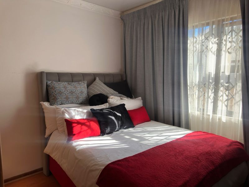 A cozy bedroom featuring natural light through a window with installed curtain tracks and decorative cornice detailing.