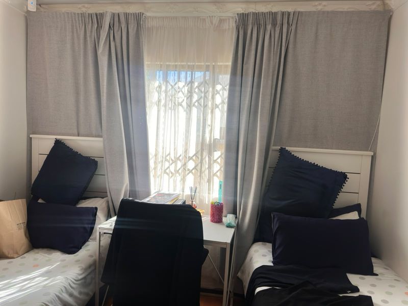 A bedroom featuring a window with a security gate and decorative ceiling cornicing.