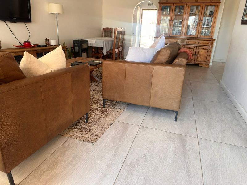 A living room area featuring large format floor tiles and an arched doorway leading to an adjacent space.